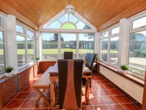 ein Esszimmer mit Fenstern und einer Holzdecke in der Unterkunft Buarthau Cottage in Caernarfon