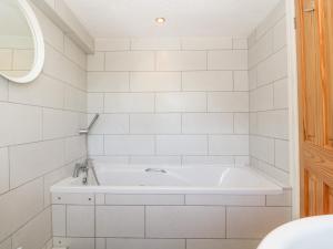una vasca bianca in un bagno piastrellato bianco di Buarthau Cottage a Caernarfon Altre 31 foto
