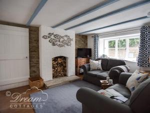 sala de estar con sofá y chimenea en Lilac Cottage, en Burton Bradstock