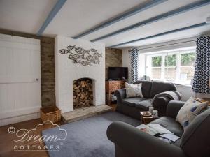 a living room with a couch and a fireplace at Lilac Cottage in Burton Bradstock