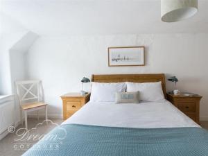 1 dormitorio con 1 cama grande con manta azul en Lilac Cottage, en Burton Bradstock