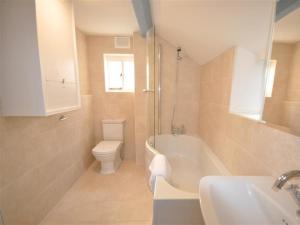 a bathroom with a tub and a toilet and a sink at Lilac Cottage in Burton Bradstock +21 photos