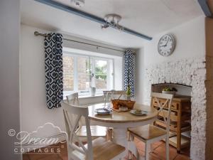 a dining room with a table and a fireplace at Lilac Cottage in Burton Bradstock