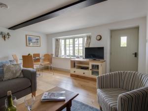 a living room with a couch and a tv at Little Forge in West Lulworth