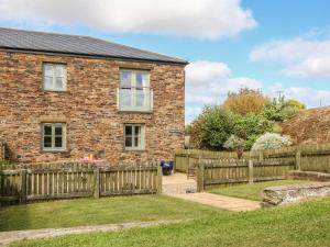 uma casa de tijolos com uma cerca de madeira em Hawthorn Cottage em Truro