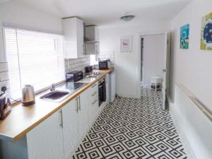 a kitchen with white cabinets and a black and white floor at Flat 1 in Bridlington