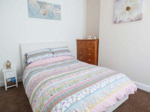 a bedroom with a bed and a dresser with two pictures at Flat 1 in Bridlington