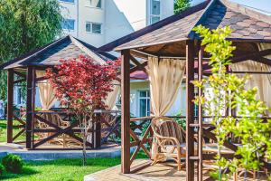 a wooden gazebo with chairs and red flowers at Alean Family Resort & SPA Riviera 4* Ultra All Inclusive in Anapa
