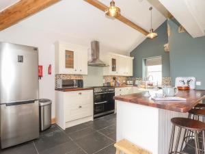 a kitchen with white cabinets and a stainless steel refrigerator at Swallows Nest in Penzance