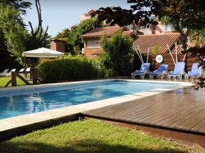 una piscina con sillas azules y una terraza de madera en Cabañas Mar de Luna, en Villa Gesell