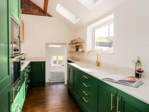 una cocina con armarios verdes y una ventana en West View Cottage, en Settle
