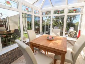 a conservatory dining room with a wooden table and chairs at Cesail Y Mynydd in Rhyl