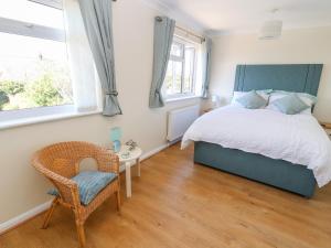 a bedroom with a bed and a chair and windows at Cesail Y Mynydd in Rhyl