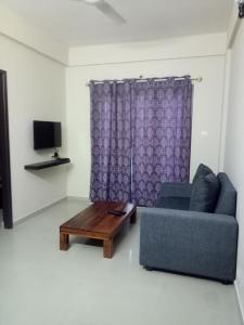 - un salon avec un canapé bleu et une table basse dans l'établissement Tranquil Serviced Apartments, à Bangalore