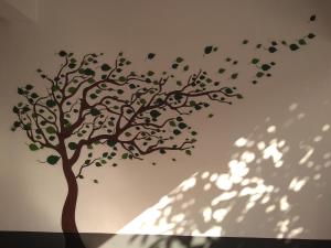 un arbre au pochoir sur un mur avec son ombre dans l'établissement Tranquil Serviced Apartments, à Bangalore