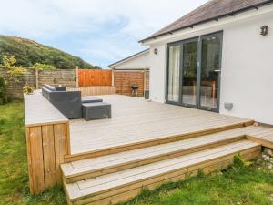 a wooden deck with a chair on a house at Doldeg in Criccieth