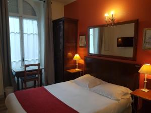 Habitación de hotel con cama y espejo en Villa Eden, en Niza