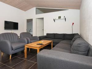 uma sala de estar com um sofá, cadeiras e uma mesa em Five-Bedroom Holiday home in Blåvand 22 em Blåvand