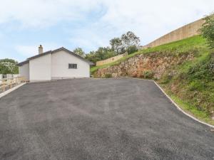 a driveway with a white garage next to a hill at Sannans Lodge in Llandudno