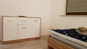 a bedroom with a white cabinet and a bed at Apartament Fibra Frappe in Rybnik