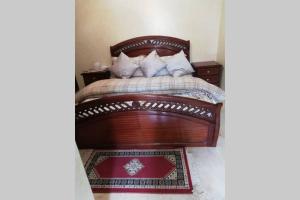 1 dormitorio con cama de madera y alfombra roja en La Siesta Bel appartement bord de mer avec piscine en Mohammedia