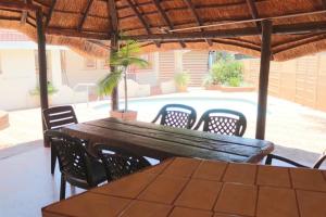 a wooden table and chairs under a wooden umbrella at Die Huis - Self Catering in Bela-Bela