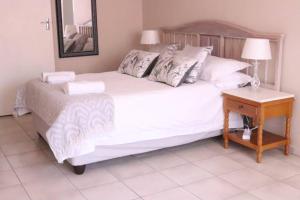 Un dormitorio con una gran cama blanca y una mesa en Die Huis - Self Catering, en Bela-Bela