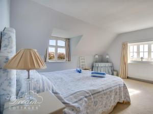 um quarto com uma cama, um candeeiro e 2 janelas em Pitt Cottage em Ringstead