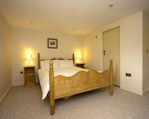 a bedroom with a large bed with two tables and two lamps at Goldcrest in Meerbrook