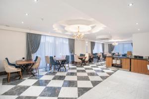 uma sala de jantar com mesas e cadeiras num piso de xadrez em The Sansa Hotel & Spa em Manavgat