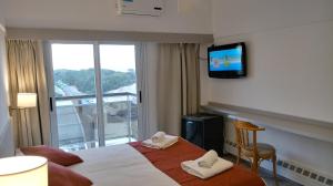 Habitación de hotel con cama y TV en la pared en Gran Hotel Fontainebleau en San Clemente del Tuyú