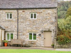 a stone house with a bench in front of it at Croft Cottage in Skipton