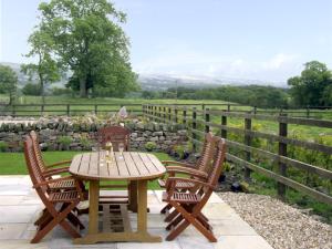 a wooden table and two chairs with a table and a fence at Honeystone in Leek