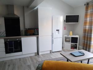 una cocina con armarios blancos y una mesa en una habitación en Swindon Theobald House - EnterCloud9SA, en Swindon
