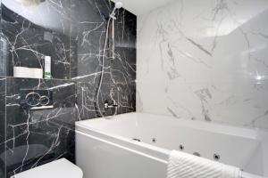 baño con bañera blanca y paredes de mármol negro. en Arena Summit Apart Hotel en Kiev