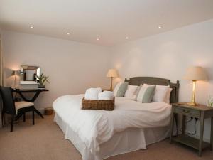 a bedroom with a large white bed with a desk at Homefield House in Thurlestone