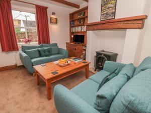 a living room with two blue couches and a table at 31 Peth Head in Wooler