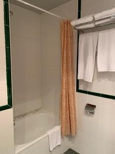 y baño con bañera, ducha y toallas. en Hotel Área de Calahorra, en Calahorra