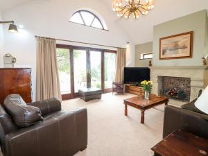 a living room with a leather couch and a fireplace at Frog Meadow Barn in Biddulph