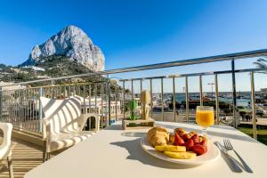 a table with a plate of food and a glass of orange juice at Hotel Porto Calpe in Calpe