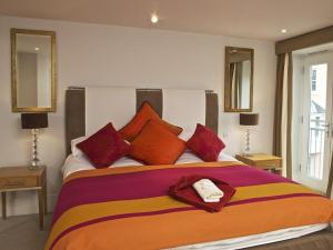 a bedroom with a large bed with red and orange pillows at Diddly Squat, 43 Dart Marina in Dartmouth