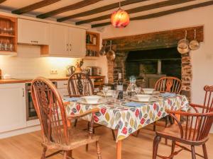 a dining room with a table and chairs and a kitchen at Hope Cottage in Ashreigney