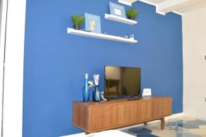 un salon avec une télévision sur un mur bleu dans l'établissement Be Blu Apartment, à Naples