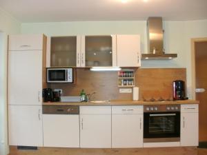een keuken met witte kasten, een wastafel en een magnetron bij Ferienwohnung Klaus in Oy-Mittelberg