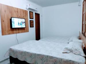 Imóveis Por Temporada em Santarém no Pará في سانتاريم: غرفة نوم بسرير وتلفزيون بشاشة مسطحة
