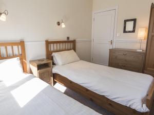 a bedroom with two beds and a dresser and a door at 4 Armada House in Hope Cove