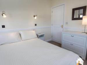 a white bedroom with a white bed and a lamp at 4 Armada House in Hope Cove