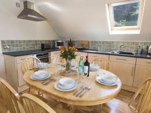 a kitchen with a wooden table with plates and wine glasses at 4 Armada House in Hope Cove