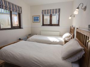 a bedroom with two beds and two windows at 4 Armada House in Hope Cove