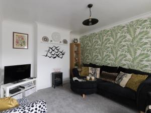 a living room with a black couch and a tv at Sunny Days in Weymouth